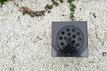 Shallow focus of a new cremation urn seen on a gravel filled memorial at a church. The holes in the...