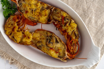 Lobster thermidor, a classic lobster dish in which a cooked lobster is halved down middle. The meat is removed, chopped, and added to a creamy cheese sauce along with shallots, mushrooms, and sherry. 