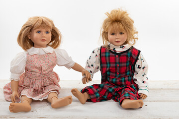 Collection of multiple dolls sitting on a rough white wooden table isolated on white with copy space