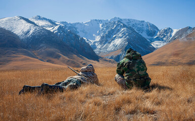 Hunters use binoculars to observe wild ungulates in the mountains.