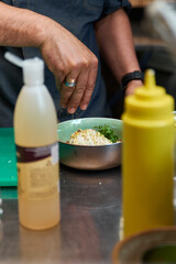 The hand of a male chef sprinkles pistachios for dessert in a restaurant kitchen.