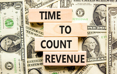 Time to count revenue symbol. Concept word Time to count revenue on wooden blocks. Beautiful background from dollar bills. Business and time to count revenue concept. Copy space.