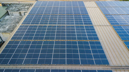 Fototapeta premium Aerial view of a solar panel photovoltaic with reflection on building roof top.
