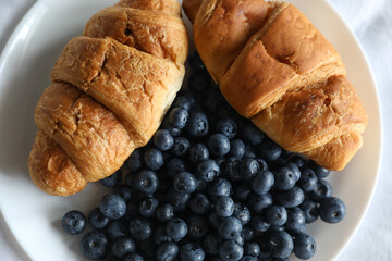 breakfast in bed - croissants and blueberries on a plate