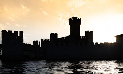 Fototapeta na wymiar Italy - Sirmone castle silhouette on the Garda lake at sunset. Medieval architecture with tower.