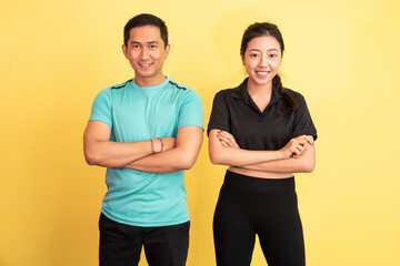 Obraz premium smiling asian woman and man standing with hands crossed on isolated background