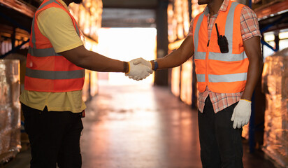 Teamwork of Black workers shaking hands in large warehouse store industry.Rack of stock storage. Cargo in ecommerce and logistic concept. Depot. People lifestyle. Shipment service for container
