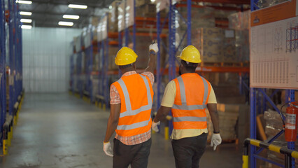 Teamwork of Black workers working in large warehouse store industry.Rack of stock storage. Interior of cargo in ecommerce and logistic concept. Depot. People lifestyle. Shipment service for container