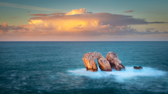 The seastacks Urro Mayor and Urro Menor in the sea off the coast at the village of Liencres, Spain at sunset