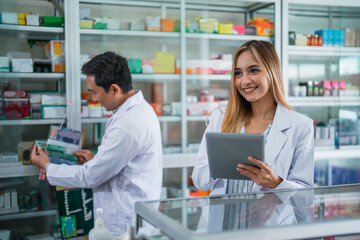 Attractive female pharmacist in uniform working using digital tablet in pharmacy