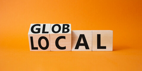 Global and Local symbol. Turned wooden cubes with words Global and Local. Beautiful orange...