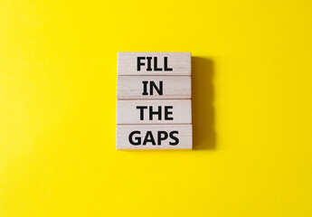 Fill in the gaps symbol. Concept words fill in the gaps on wooden blocks. Beautiful yellow background. Business and fill in the gaps concept. Copy space.
