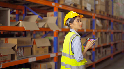 Portrait of Asian woman worker working in large warehouse retail store industry factory. Rack of stock storage. Cargo in ecommerce and logistic concept. Depot. People lifestyle. Shipment service.