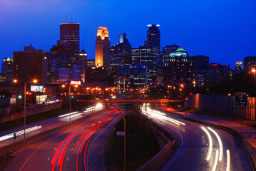 Fototapeta na wymiar Traffic rushes along a highway to and from the downtown city skyline of Minneapolis, Minnesota at night