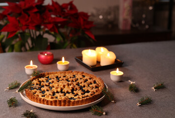 christams tart on the table near candles and red flowers