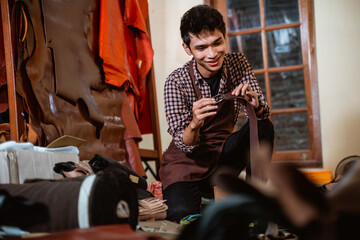 asian craftsman checking a leather belt craft in tannery workshop