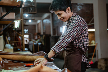Fototapeta na wymiar Asian craftsman loves to work with leather making basic shapes on a workbench