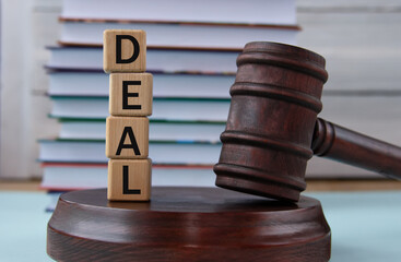 The word DEAL on wooden cubes against the background of the judge's gavel and stand