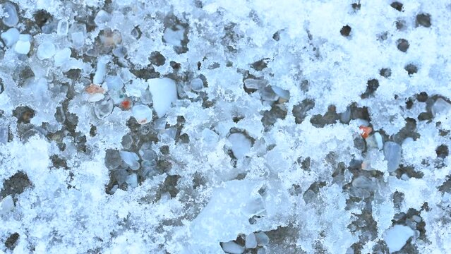 macro overhead closeup view of rock salt ice-melt on concrete with snow