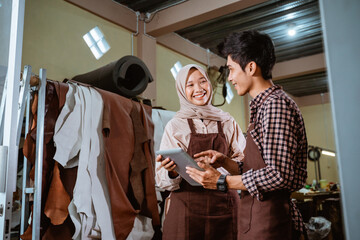 craftswoman in veil and craftsman talking and using a tablet together at the workshop