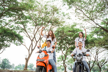 Two pairs of high school students in uniform riding reckless motorbikes on the highway