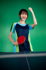 Female player holding paddle with fist up while winning a ping pong match