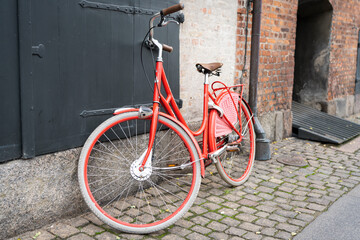 Fototapeta na wymiar old red bicycle parked on cobblestone street in Copenhagen