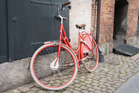 old red bicycle parked on cobblestone street in Copenhagen