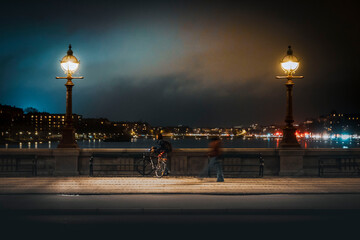 Cyclist stops on a bridge at night to enjoy the view of Copenhagen, Denmark 