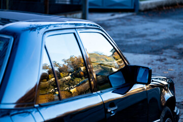 Fototapeta premium Reflection of Bavarian mountains in window of vintage European sedan, Salzburg, Austria 