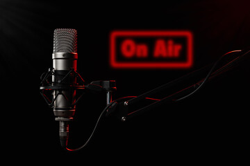 Professional large diaphragm microphone for podcast on black background backlighted with red colour