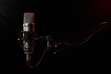 Professional large diaphragm microphone for podcast on black background backlighted with red colour