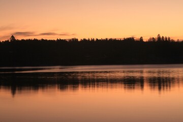 Fototapeta na wymiar sunrise over calm water - Lysaker