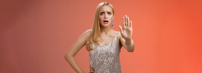 Freaked out displeased bothered insecure blond woman in silver glittering dress extend palm stop...