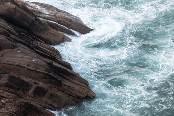 Waves impacting against the rock cliff in Atlantic ocean