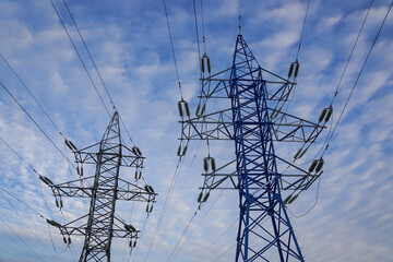 Two electric power transmissions against blue sky with light clouds, energy cooncept