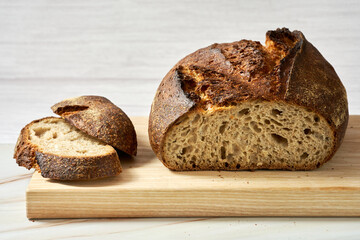 Sliced loaf of freshly baked homemade bread on wooden cutting board. Close-up