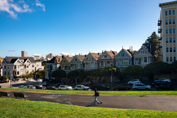 San Francisco, USA. September 20, 2022. Woman walking on hilly road with Painted Ladies Houses in a...