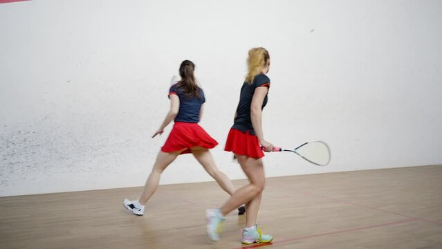Professional female squash players move around court quickly