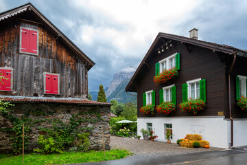 Traditional Swiss homes with wood siding and colorful shutters and flowers in the Swiss countryside in the Alps near Mt Titlis.