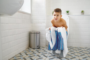 Frowning little boy sitting on toilet trying to poop © Nomad_Soul
