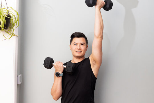 Asian American trans man lifting weights.