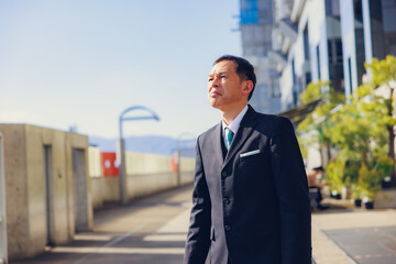 Middle-aged Asian man in black business suit at Kyoto station building, Japan.