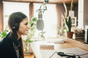 Young female radio host. Guest on radio station talking about interesting topic. Podcast hosting influencer speaker. Modern news broadcasting media. Professional studio podcasting interview