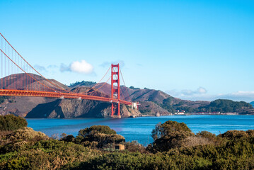 View of historic Golden Gate Bridge over beautiful San Francisco Bay with mountains and blue sky in the background during sunny day