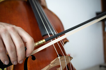 close up of a violoncello player, right hand holding cello bow showing good technique musical instrument