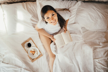Optimistic young woman enjoying relaxed morning.Morning ritual,gratefulness and mindfulness concept.Leasure wellnes day off.Quality free time.Relaxed day at home.Cosy home comfort.Reading a book - obrazy, fototapety, plakaty