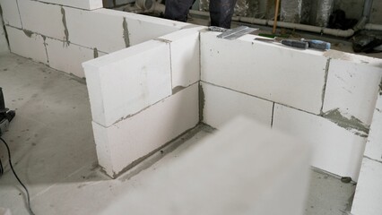 A construction site on which the walls are built of aerated concrete bricks. Empty walls of new buildings from the gas block. Installation of a wall of white blocks in a new apartment.