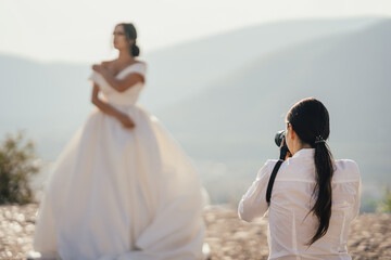 Professional photographer making pictures of the bride on the wedding day photo session. Wedding photograpy concept. Bride posing outdoors.
