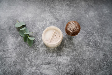  Natural homemade face loose powder with blush (powder brush) on grey marble background with eucalyptus leaves.             